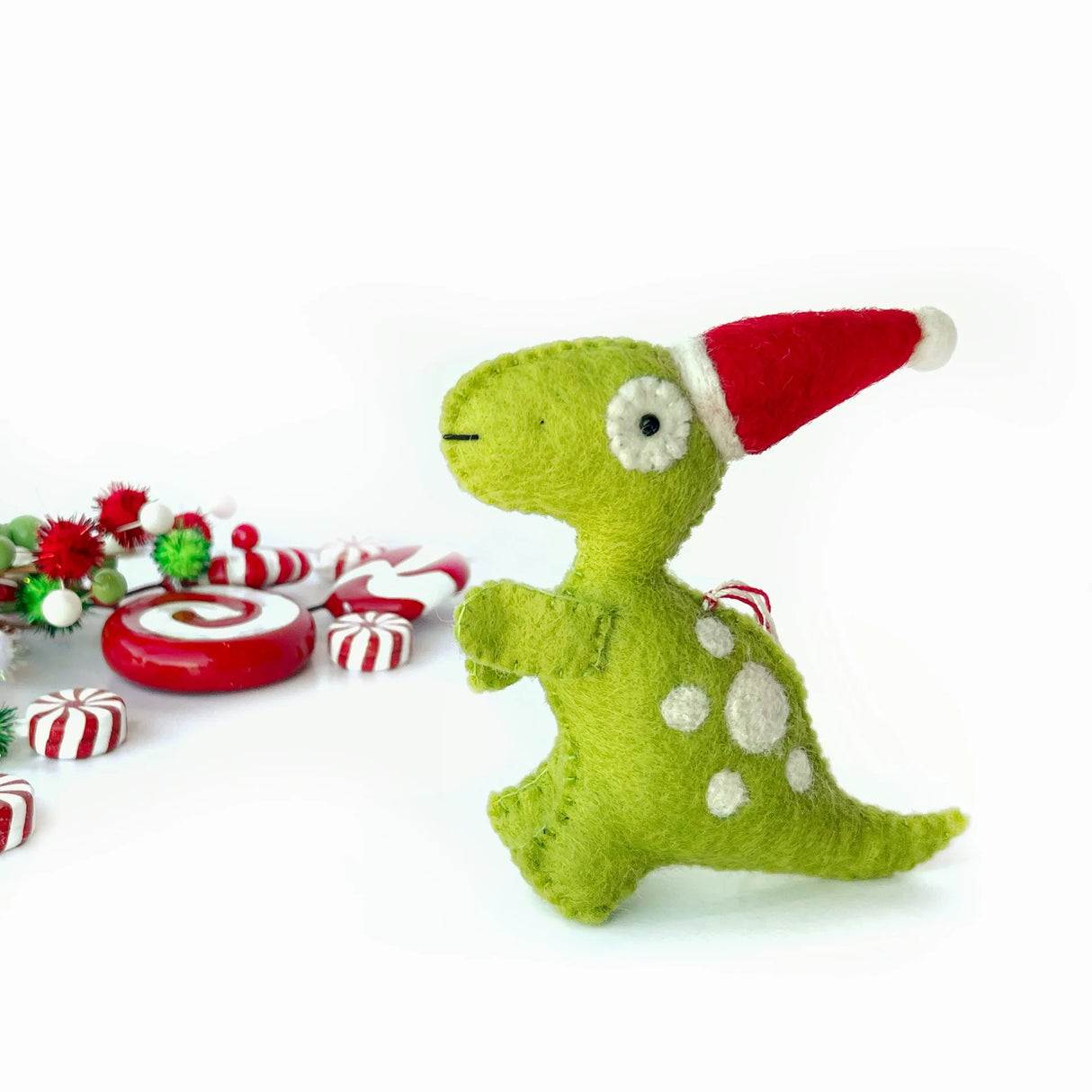 T Rex with Hat Felt Ornament handmade from green sheep wool wearing a red Santa hat with white spots and holiday decor.