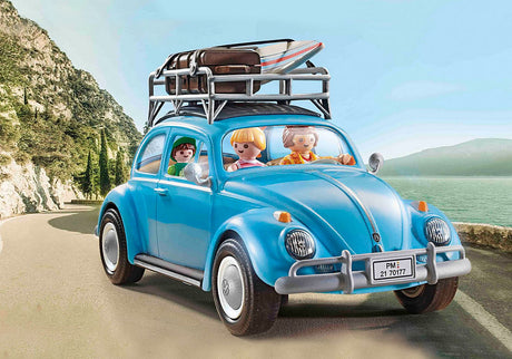 Volkswagen Beetle PLAYMOBIL toy car with family figures, blue body, roof rack, suitcase and surfboard on scenic coastal road.