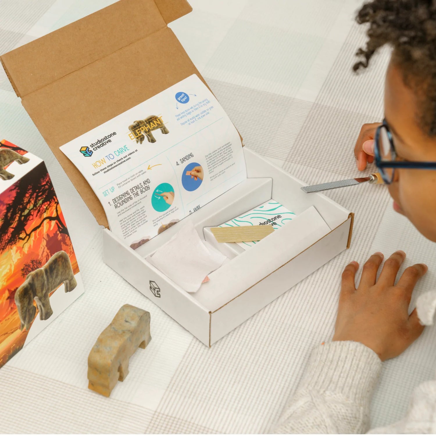 Soapstone Carving Kit Elephant showing kid using carving tools with elephant soapstone and instructions included