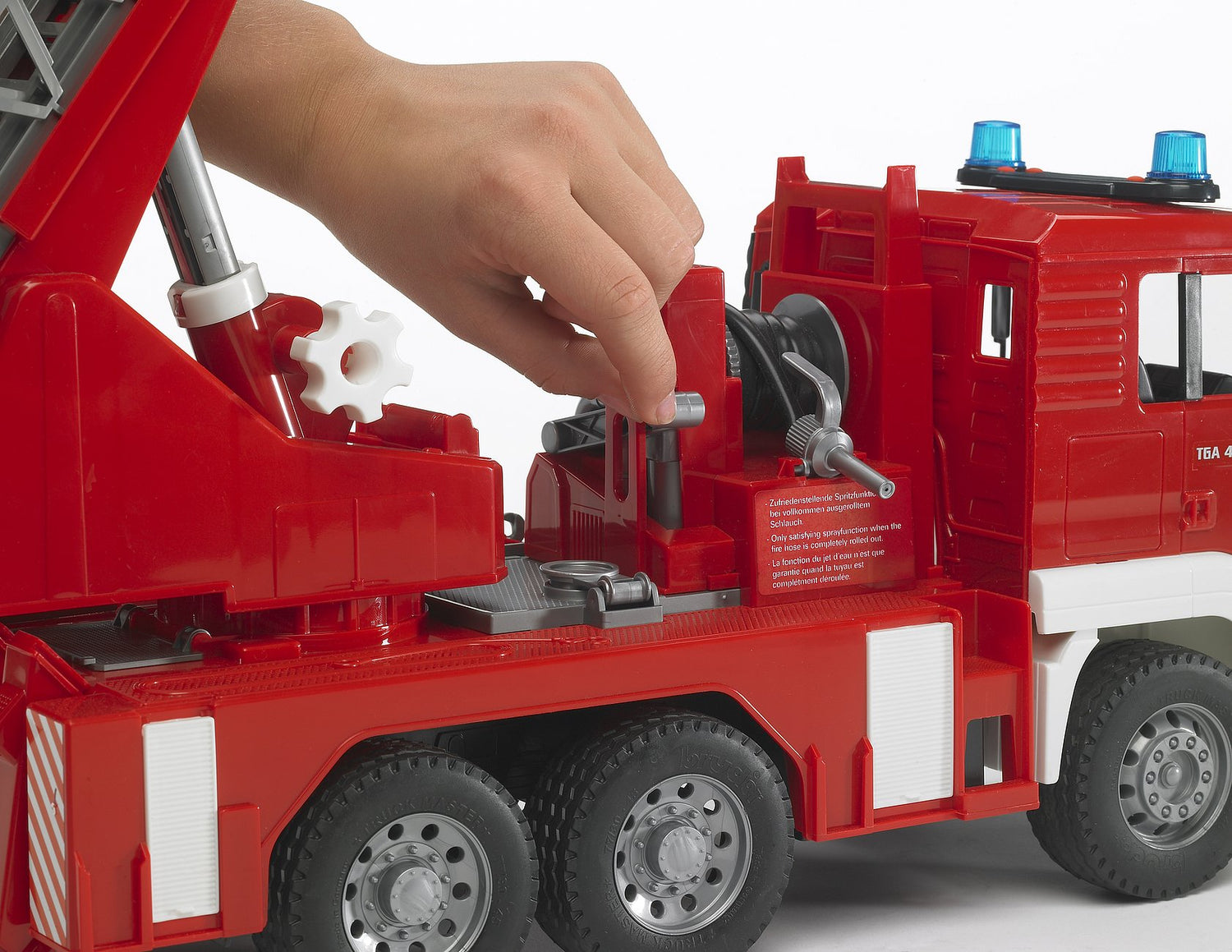 Hand operating the tipping driver's cab of the Fire Engine toy with turntable ladder and water pump details.