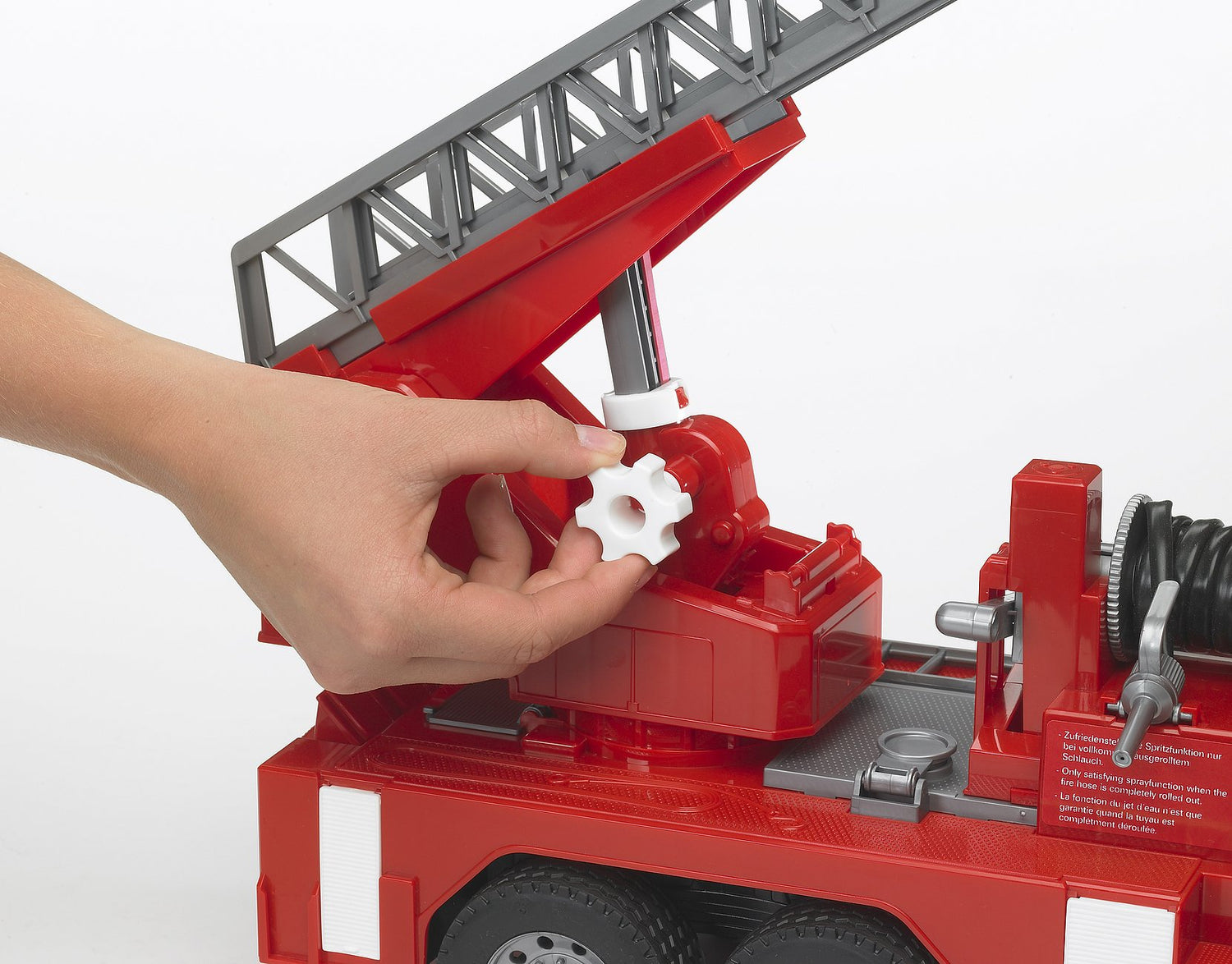 Hand adjusting the turntable ladder on the Fire Engine toy with detailed ladder and water pump features visible.