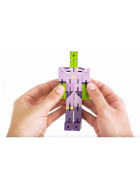 Hands holding a purple and green wooden figure of Puzzle Planet Emperor brainteaser puzzle toy.