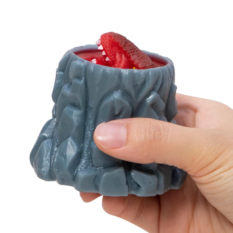 Hand squeezing Volcanic Dino Poppers toy with a red T-Rex popping out of a grey volcano for kids ages 3 and up.