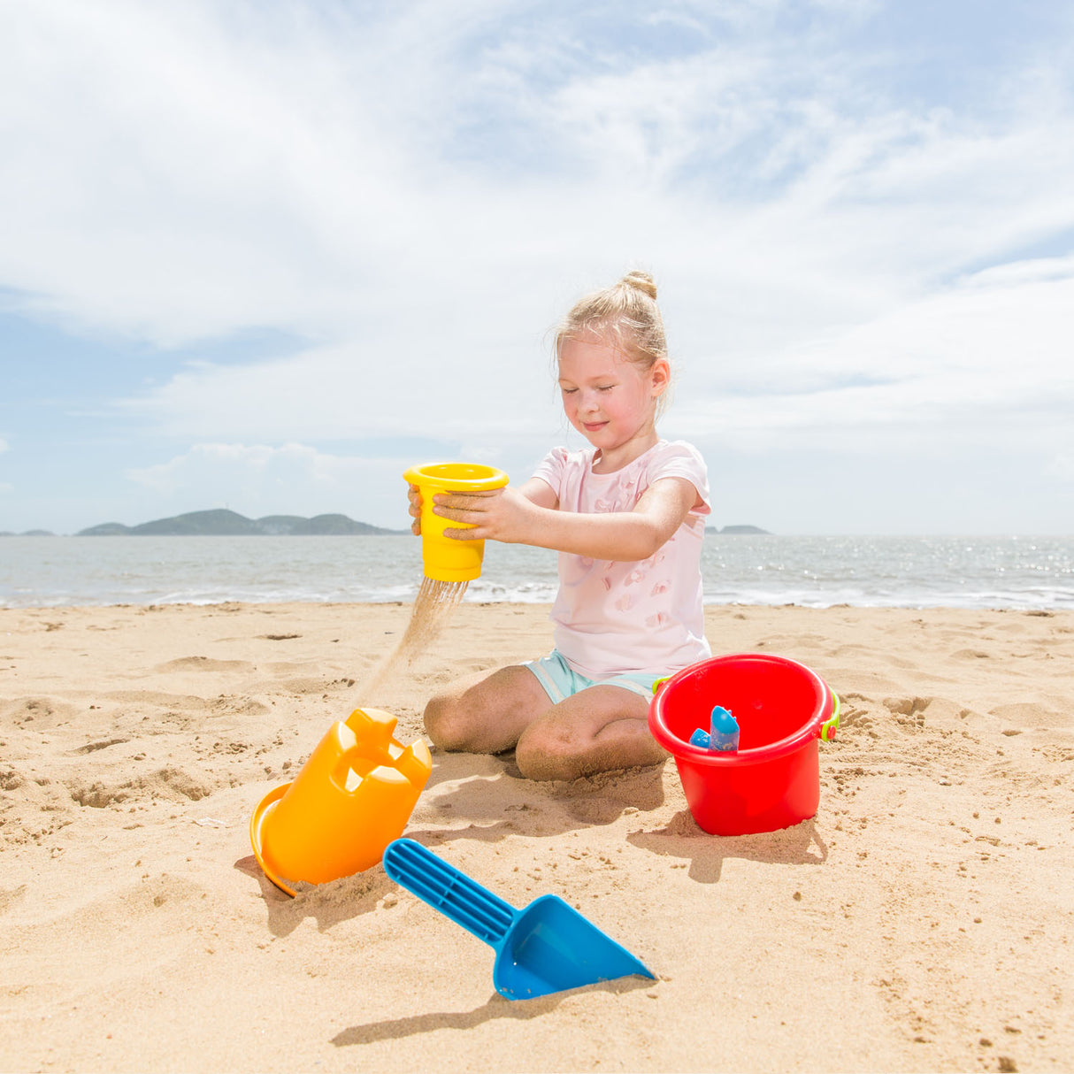 A child playing with colorful sand toys on the beach using the 5-in-1 Beach Set for hours of fun.