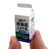 Japanese Eraser Drink showing a miniature milk carton puzzle eraser toy held between fingers, eco-friendly and handmade.