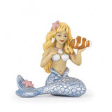 Mermaid figurine with blonde hair, shell accessories, and holding a clownfish from the enchanted world collection.