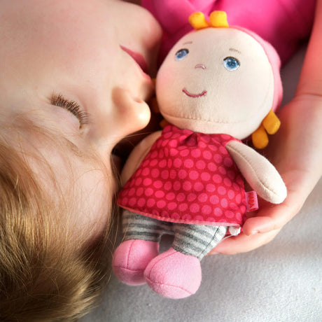 Mini Doll Hertha cuddly soft doll with a polka dot dress held by a sleeping child, perfect for babies and toddlers.