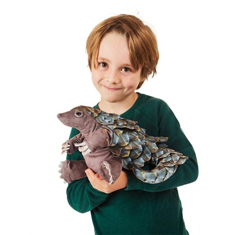 Child holding a detailed Pangolin plush toy with scaly skin, moveable head, and wrapped tail, perfect for ages 3 and up.