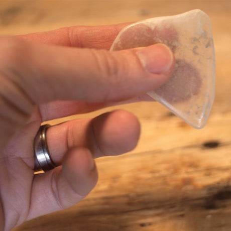 Hand holding TV Rock demonstrating the fiber-optic effect projecting images onto its surface on wood table.