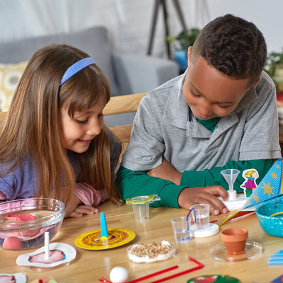 Two children engaged in hands-on experiments with educational tools using Stepping into Science kit at home.