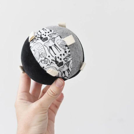 Hand holding the Organic Taggy Ball | Nordic, featuring black and white animal prints with textured tags for sensory play.